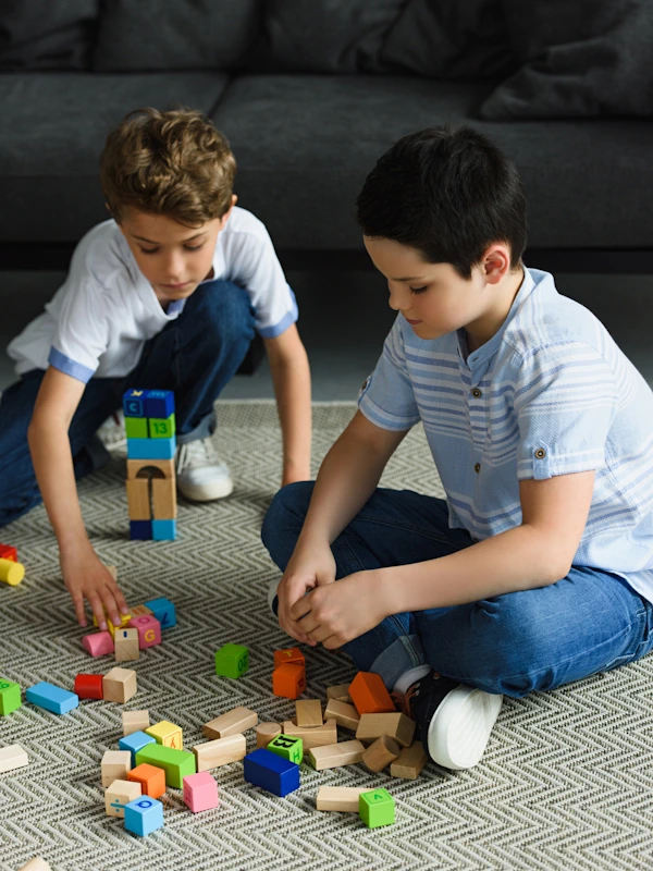 two young boys playing with wooden blocks on newly carpeted floor in living room