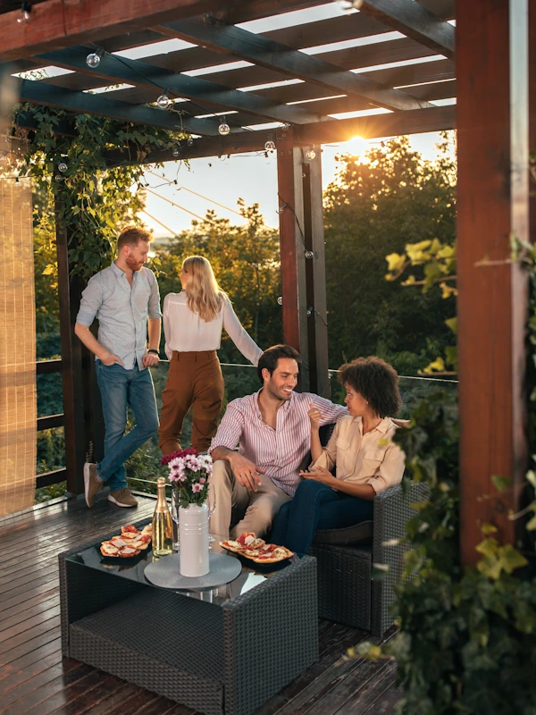 two young couples enjoying relaxing time in outdoor living area corner deck with wood flooring overlooking trees