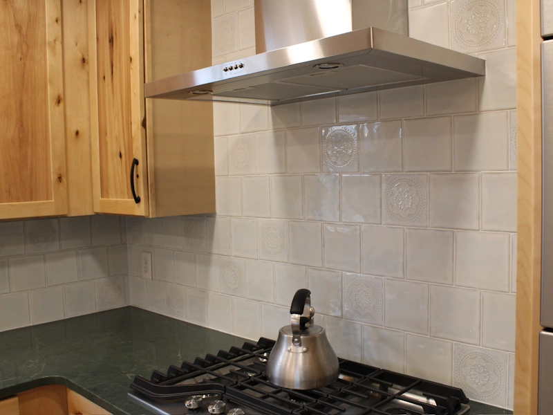 Custom tile insert medallions installed on backsplash tile of kitchen remodel