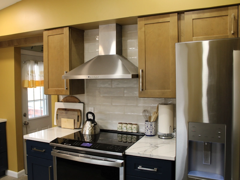 Large subway tiles installed as backsplash around hood area above stove in kitchen remodel